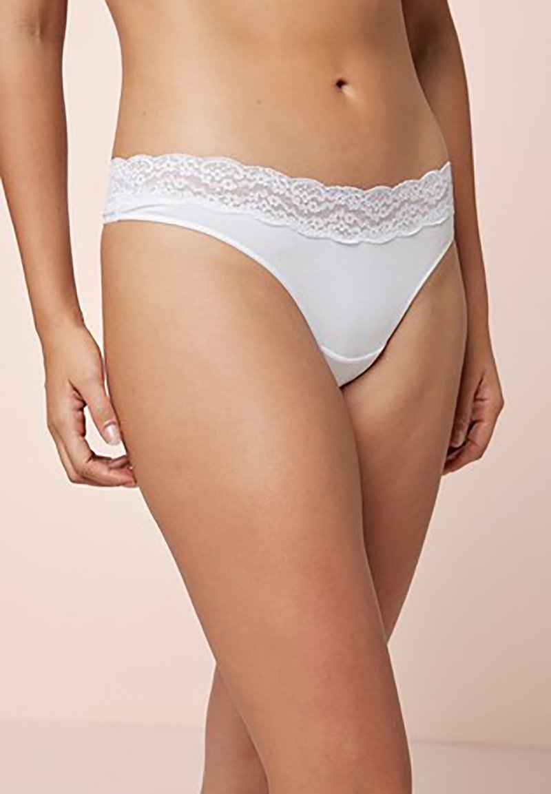 String en dentelle blanche avec une finition en dentelle, fabriqué en tissu doux, présentant un design taille basse et une texture lisse, idéal pour un usage quotidien.