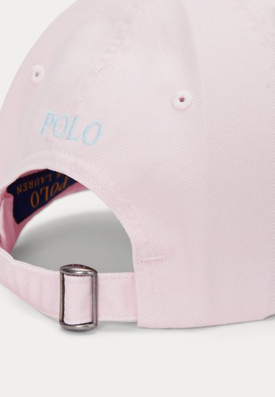 Pink cotton baseball cap with light blue "POLO" embroidery. Features a metal buckle and a textured fabric. Rear opening is visible.