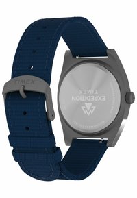 Baksidan av en Timex Expedition armbandsklocka med ett blått vävt textilarmband och kabinett av rostfritt stål som visar varumärkes- och modellinformation.