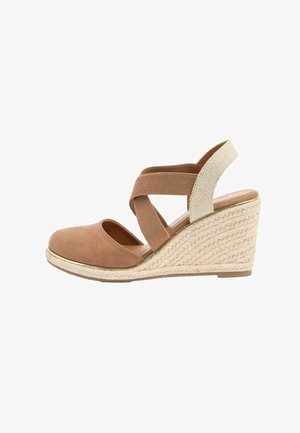 Sandale platformă cu talpă wedge de culoare taupe, platformă din iută împletită, bretele elastice încrucișate și vârf închis pe un fundal alb.