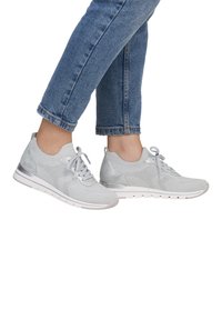 Hellgraue Sportschuhe mit einem Strickobermaterial, textilen Details und einer glatten Gummisohle. Sie verfügen über eine Schnürung und einen gepolsterten Fersenbereich.