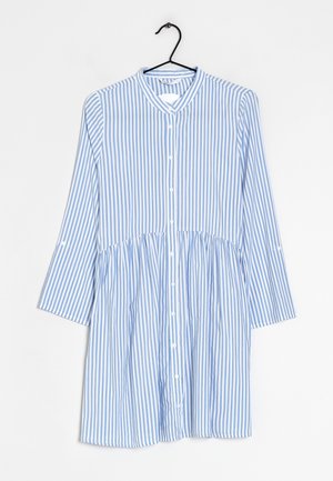 Sukienka z pionowymi niebiesko-białymi paskami, zapinana na guziki, z długimi rękawami, wisząca na czarnym wieszaku na białym tle.
