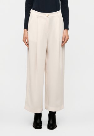 Kremfargede vidbukser i glatt stoff, høy midje og sentral knapp. Har sidelommer og en ren, skreddersydd finish.