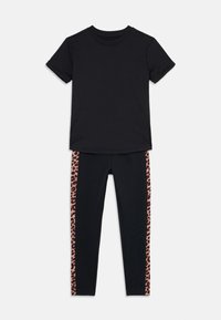 T-shirt noir à manches retroussées associé à un legging noir avec des rayures latérales en imprimé léopard. Les deux articles sont en tissu extensible et confortable.