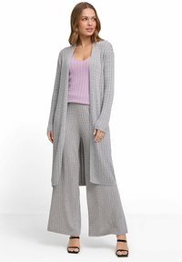 Grau gestrickte Strickjacke mit langen Ärmeln und offenem Vorderteil, getragen über einem helllila gerippten Oberteil und passenden weit geschnittenen Hosen, mit strukturierten Mustern.