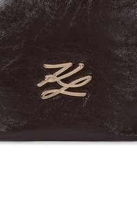 Borsa in pelle di colore marrone scuro con texture, caratterizzata da un prominente logo dorato sulla parte anteriore. Superficie liscia con una leggera lucentezza, design sofisticato.