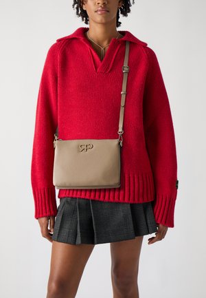 Beige Leder Umhängetasche mit strukturierter Oberfläche und geprägtem Logo, kombiniert mit einem roten Strickpullover und einem plissierten schwarzen Karorock.