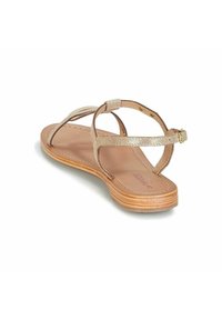 Platt, gyllene sandal med korsande remmar och spänne. Utrustad med en jämn, beige inläggssula och en strukturerad, ljus färg på sulan.