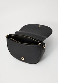 Borsa a tracolla in pelle nera con forma arrotondata, chiusura superiore con zip e dettagli in metallo dorato. L'interno presenta più scomparti per l'organizzazione.