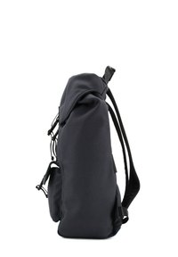 Zaino in tessuto navy con forma arrotondata, manico superiore, spallacci regolabili e tasche laterali esterne. Presenta una superficie con texture e un design minimalista.