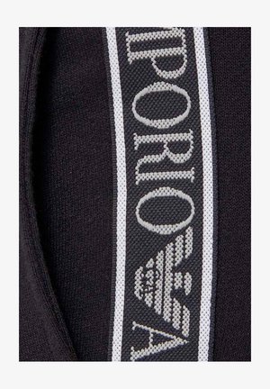 Tejido negro con una prominente banda de logos en gris y blanco que presenta la palabra "Emporio" y un diseño de águila estilizada.