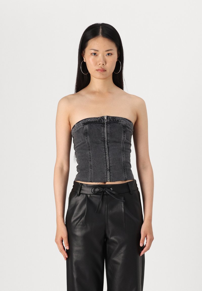 Top senza spalline in denim nero con un design aderente e dettagli di cucitura verticale. Abbinato a pantaloni in pelle nera a vita alta.
