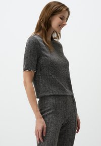 Top corto grigio testurizzato a maniche corte con vestibilità rilassata, caratterizzato da piccole perline decorative lungo l'orlo delle maniche e una finitura liscia.