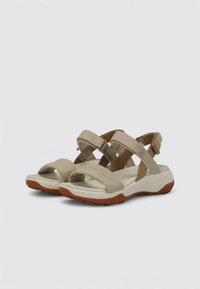 Sandalias ajustables beige con diseño de tiras cruzadas, plantilla beige acolchada y suela de goma naranja texturizada, adecuadas para uso exterior.