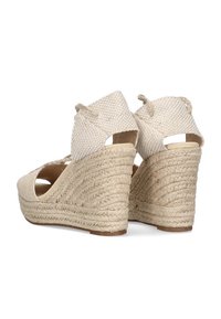 Cuñas de esparto beige con parte superior de tejido trenzado y tacón de cuerda trenzada. Diseño de talón abierto con detalles de cordones para un ajuste seguro.