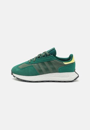 Green suede and mesh athletic shoe featuring three dark stripes, a white midsole, and a black rubber outsole with yellow accents.