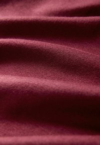 Bordo audinys su lygiu paviršiumi, pasižymintis minkštais klostėmis ir smulkiu pynimu, pabrėžiantis jo sodrią spalvą ir gilumą.