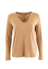 Langarm, V-hals T-shirt van beige stof met een gladde textuur. Heeft een sterontwerp op de bovenrug en drie decoratieve knopen.