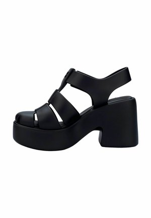 Sandales à plateforme noires avec larges brides, bout ouvert et talon incurvé. Fabriquées en matériau lisse avec une semelle texturée pour une meilleure adhérence.