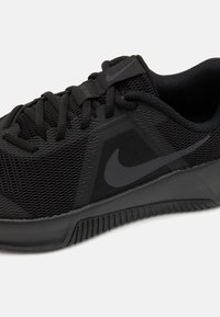 Schwarzer Sportschuh aus Mesh und synthetischem Material. Verfügt über strukturierte Akzente, flache Schnürsenkel und eine Gummisohle mit gemustertem Profil.