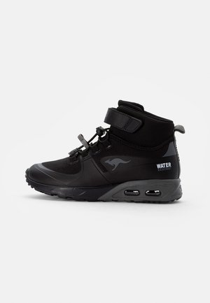 Chaussure de sport noire mi-montante avec logo kangourou, bride velcro, arrêt de lacets, semelle avec coussin d'air, et texte "water resistant" sur le talon.