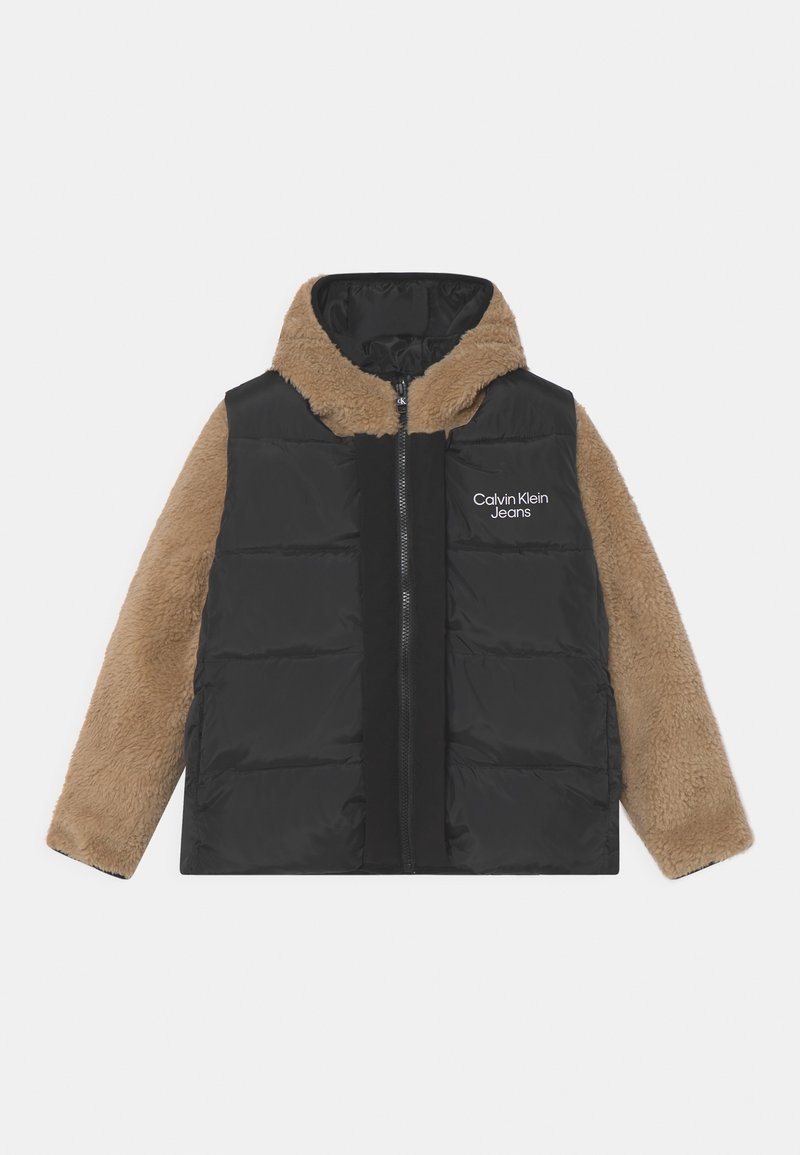 Doudoune noire avec manches et capuche en polaire beige, fermeture éclair à l'avant, et logo "Calvin Klein Jeans" sur la poitrine gauche.