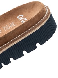 Nahaufnahme eines braunen Wildleder-Sandalen mit gepolstertem Fußbett, einer dicken schwarzen, profilierten Gummisohle und sichtbaren weißen Nähten.