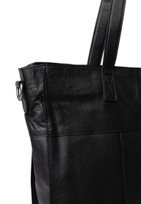 Svart läder tote-väska med texturerad yta, med en hög form, dubbla remmar och en silverfärgad metallring på sidan.