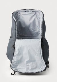 Zaino grigio con un design liscio e strutturato. Presenta un ampio scomparto principale e tasche laterali in rete, con chiusura a zipper e tessuto resistente.