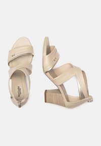 Beige h�ælede sandaler med krydsede stropper, metalliske detaljer og en tekstureret blokhæl. Fremstillet af blødt læder, med lukket bagparti.