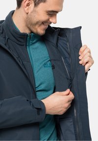 Donkerblauw lichtgewicht jack met ritssluitingen in de zakken en een fleece laag aan de binnenkant; heeft een hoge kraag en verstelbare manchetten. Verfraaid met het merkembleem.