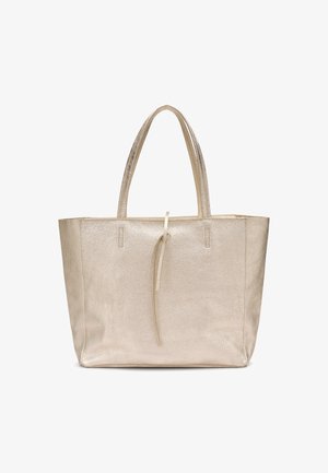 Sac cabas en cuir ton or brillant avec deux anses et une fermeture fine à nouer en haut, présenté sur un fond blanc.