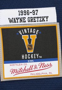 1996-97 Wayne Gretzky Etikett über einem Vintage Hockey Mitchell & Ness Philadelphia Patch auf dunkelblauem Stoff.