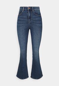 Högmidjade mörkblå jeans i denim med framfickor, knappstängning och utställda ben framför en enfärgad vit bakgrund.