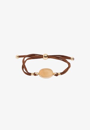Regulowana brązowa bransoletka z zamszowego sznurka z gładkim owalnym centralnym elementem z metalu w odcieniu złota oraz małymi, złotymi koralikami na końcach i w środku.