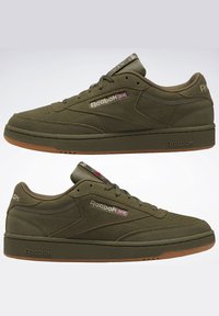 Sneaker basse Reebok in suede verde oliva con suole in gomma e logo Union Jack sui pannelli laterali, mostrate nei profili sinistro e destro.