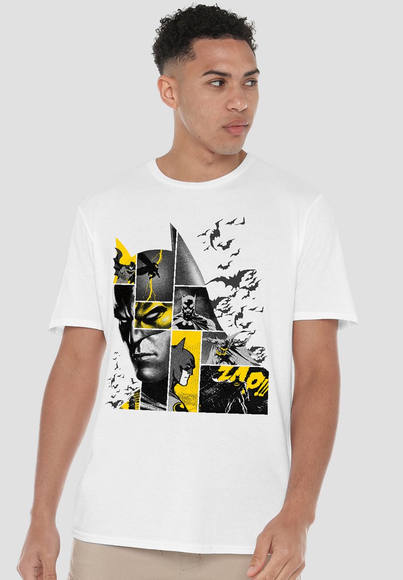 Man wearing white T-shirt with a black and yellow Batman comic-style collage and bats flying on the design.
