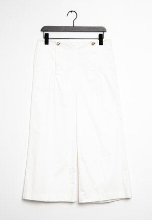 Pantaloni larghi bianchi realizzati in tessuto liscio. Presentano tasche anteriori e bottoni dorati. Appesi a una gruccia nera in plastica.