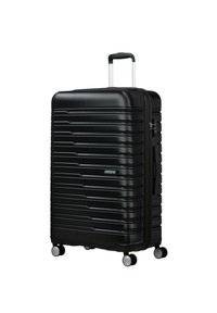 Valigia rigida nera con righe orizzontali, manico retrattili e quattro ruote. Dotata di chiusura con zip e manico laterale per il trasporto.