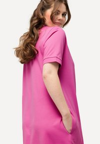 Abito rosa a maniche corte realizzato in morbido cotone misto. Caratterizzato da una vestibilità comoda, tasche laterali e scollatura rotonda.