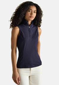 Navy ärmelloses Polo-T-Shirt mit hohem Rüschkragen, Knopfleiste und einer glatten, elastischen Stoffoberfläche. Kombiniert mit hellen Hose.