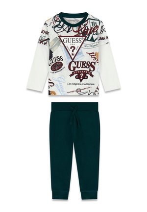 Hvid skjorte med lange ærmer med forskellige Guess-logoer og mørkegrønne bukser med snøre i taljen.