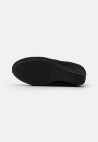 Zapato de ante negro con suela texturizada y puntera redonda. Talla 37 marcada en el costado. Material suave y diseño elástico.