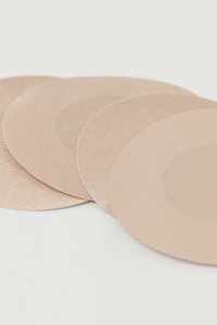 Čtyři kruhové lepící textilní náplasti v jemně růžové barvě, s hladkým povrchem a matným zakončením a centrální lepící plochou.