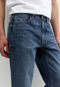 Blå denim jeans med lige ben-design, kontrastsyninger og standard fem-lomme styling. Let falmet med en glat tekstur.