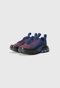 Des baskets avec un dessus en mesh dégradé de bleu et rouge, dotées d'une semelle noire et de bulles d'air translucides au niveau du talon.