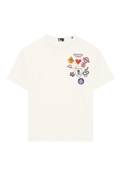 Hvid bomulds T-shirt med forskellige farverige patches, herunder tekst og grafik som en kranium, slange og nationale flag. Korte ærmer, rund hals.