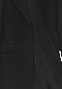 Lungo cappotto nero con revers e una pattina sulla tasca, parzialmente aperto per rivelare una fodera interna nera liscia.