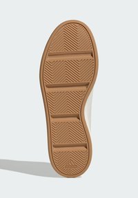 Suela de goma con patrón de espiga, con surcos horizontales para mayor tracción. El color es marrón claro con una superficie texturizada.