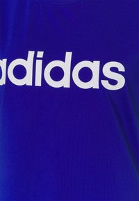 Royal blue T-shirt featuring a large white "adidas" logo, round neckline, and smooth fabric texture.